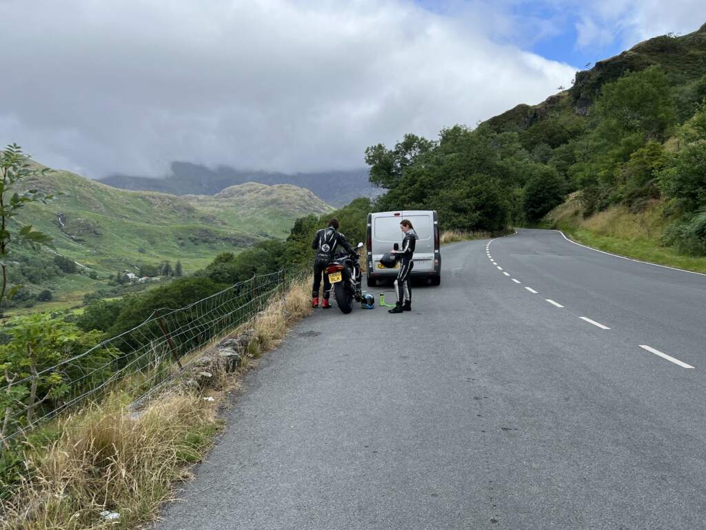 Pareja de moteros con su furgoneta camperizada en una carretera de gales