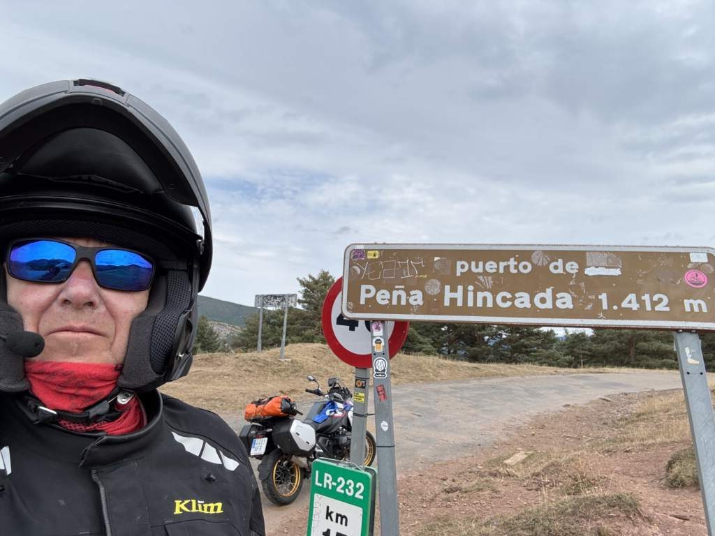 π, yo, la carretera, la altitud, el sticker, el nombre del puerto y la carretera destrozada. Esta en la sierra de los Cameros, La Rioja, y dado el estado de la ruta mejor evitarlo.